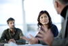 a man and a woman sitting at a table looking at a third person at the table